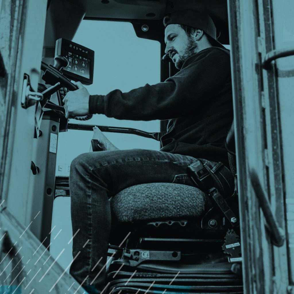 Worker sitting inside of a truck. Door is open and some computer equipment is seen